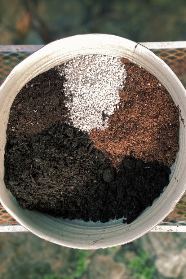 DIY potting mix ingredients separated in a round container: coco coir, perlite, organic compost, and garden soil